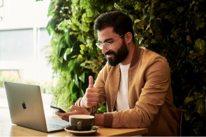 A gentleman giving the thumbs up whilst working on a laptop